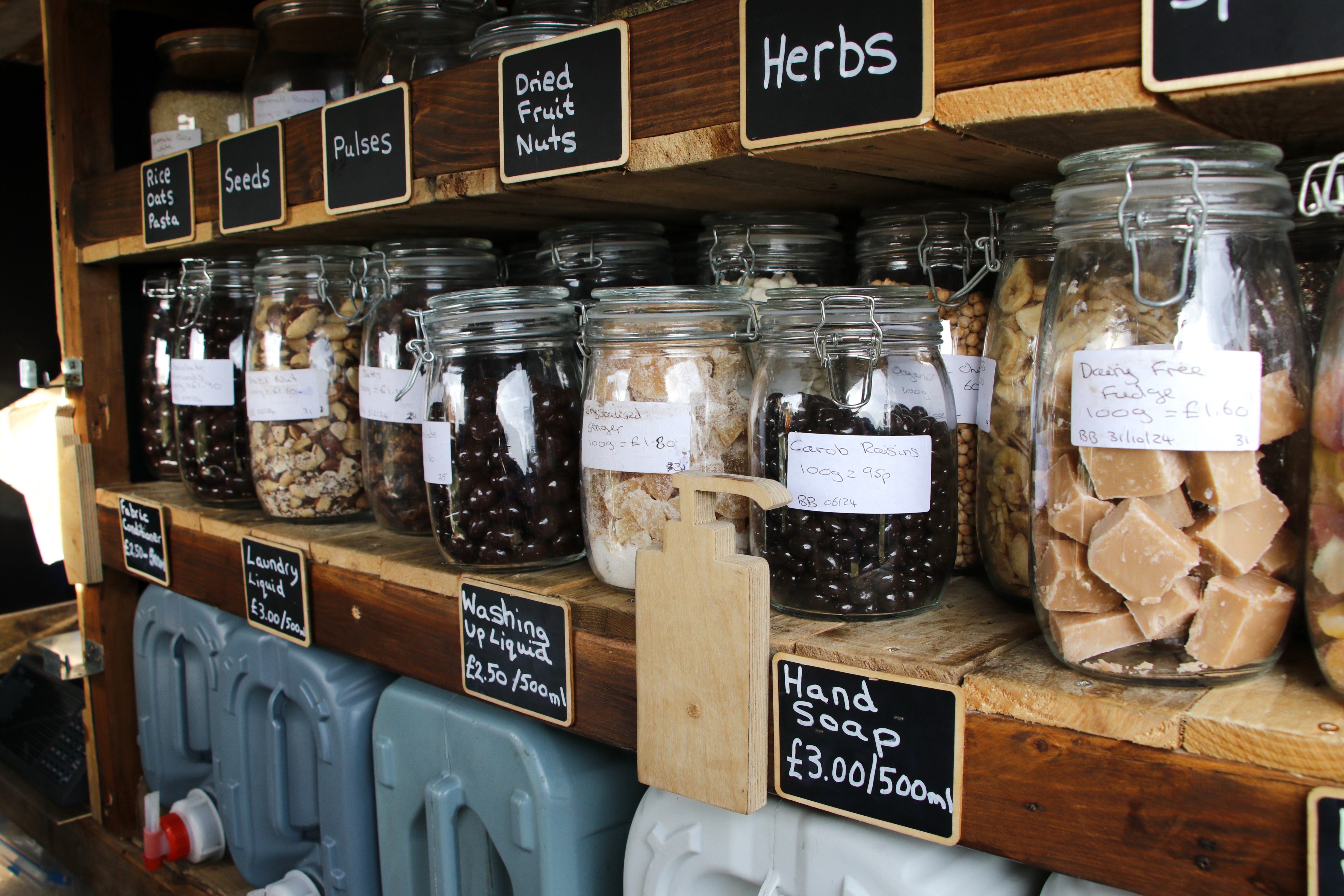 Jars filled with dry pantry goods sit are packed behind a wooden railing inside the van